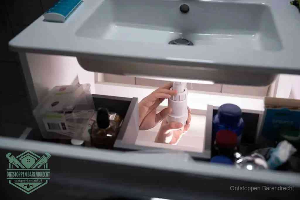 Een pompfles met zeep boven een wastafel, de heet water en afwasmiddel-methode om een vetprop in de afvoer los te maken in Barendrecht