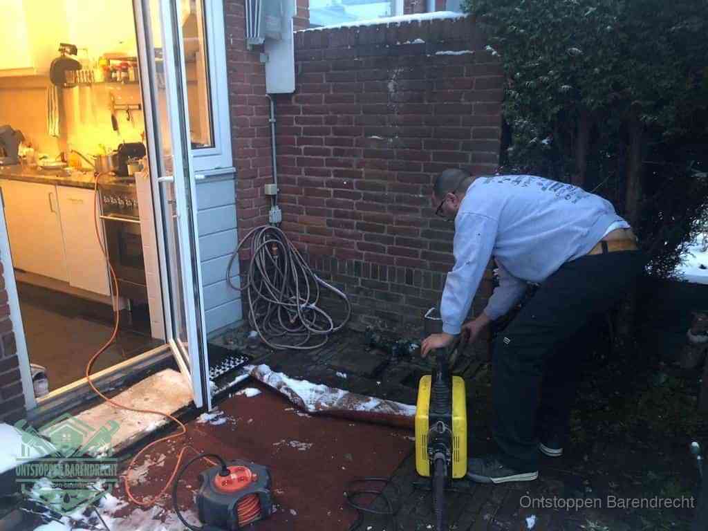 Een monteur werkt buiten bij een open riool-/grondput met een elektrische ontstoppingsmachine om een verborgen afvoerprobleem op te sporen in Barendrecht
