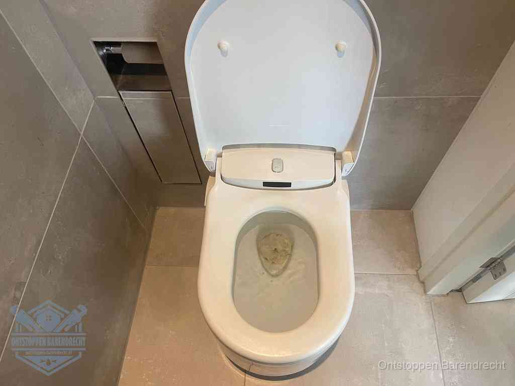 Een wit hangtoilet waarin een prop wc-papier op het water blijft drijven, een duidelijk signaal van een verstopte wc in Barendrecht