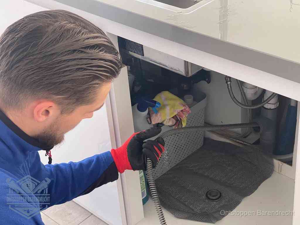 Een monteur voert een flexibele ontstoppingsveer in de afvoer om een verstopping voorbij de bocht van het toilet te bereiken in Barendrecht