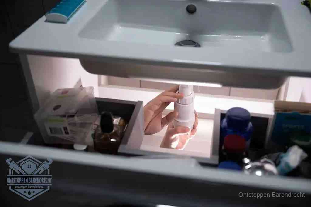 Een pompfles met zeep boven een wastafel in de toiletruimte, de warm water en afwasmiddel-methode om de wc te ontstoppen in Barendrecht
