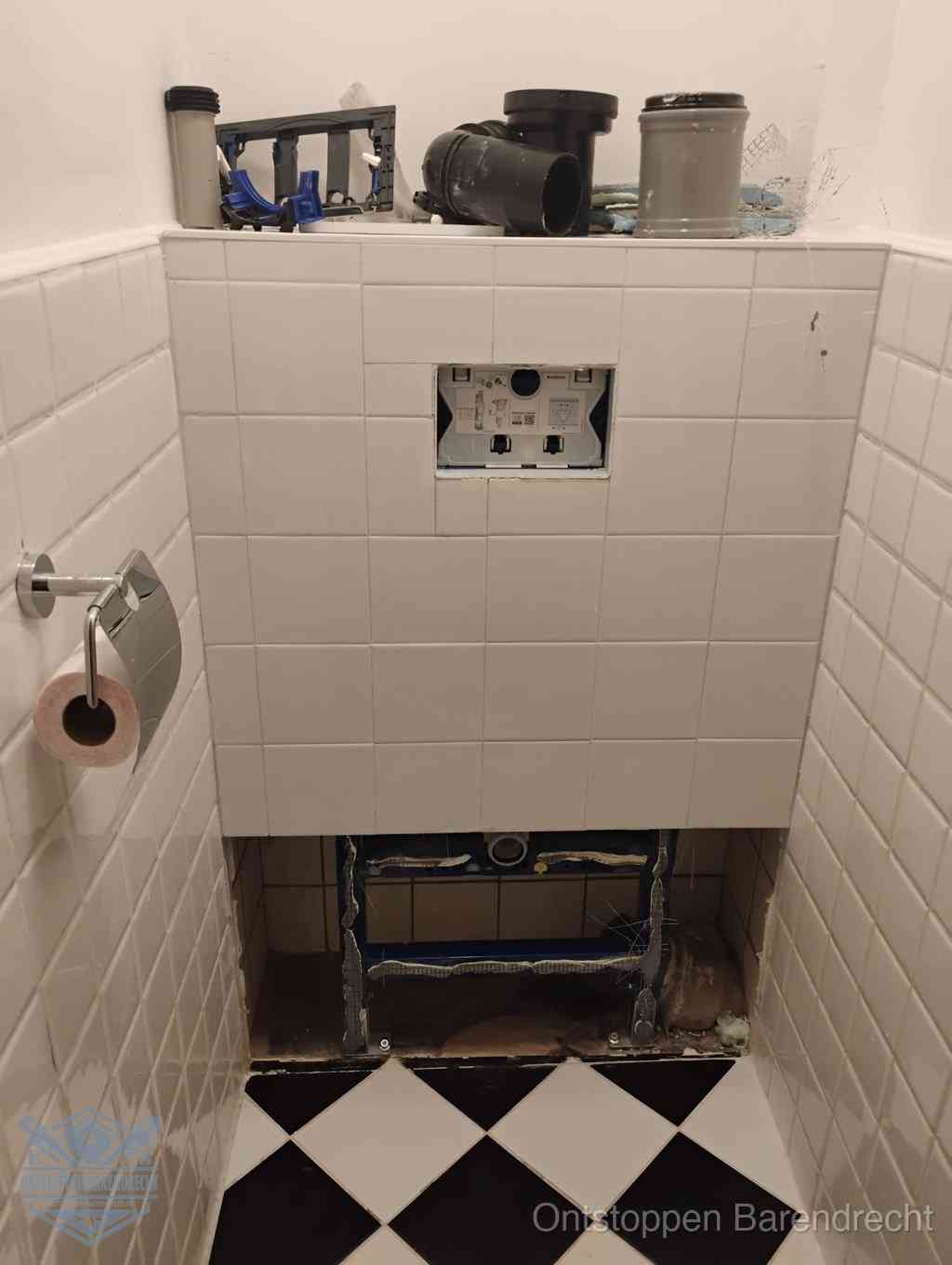 Een toiletruimte waar het hangtoilet en de inbouwreservoir-onderdelen zijn vrijgelegd voor onderhoud, periodiek nazicht voorkomt een wc-verstopping in Barendrecht